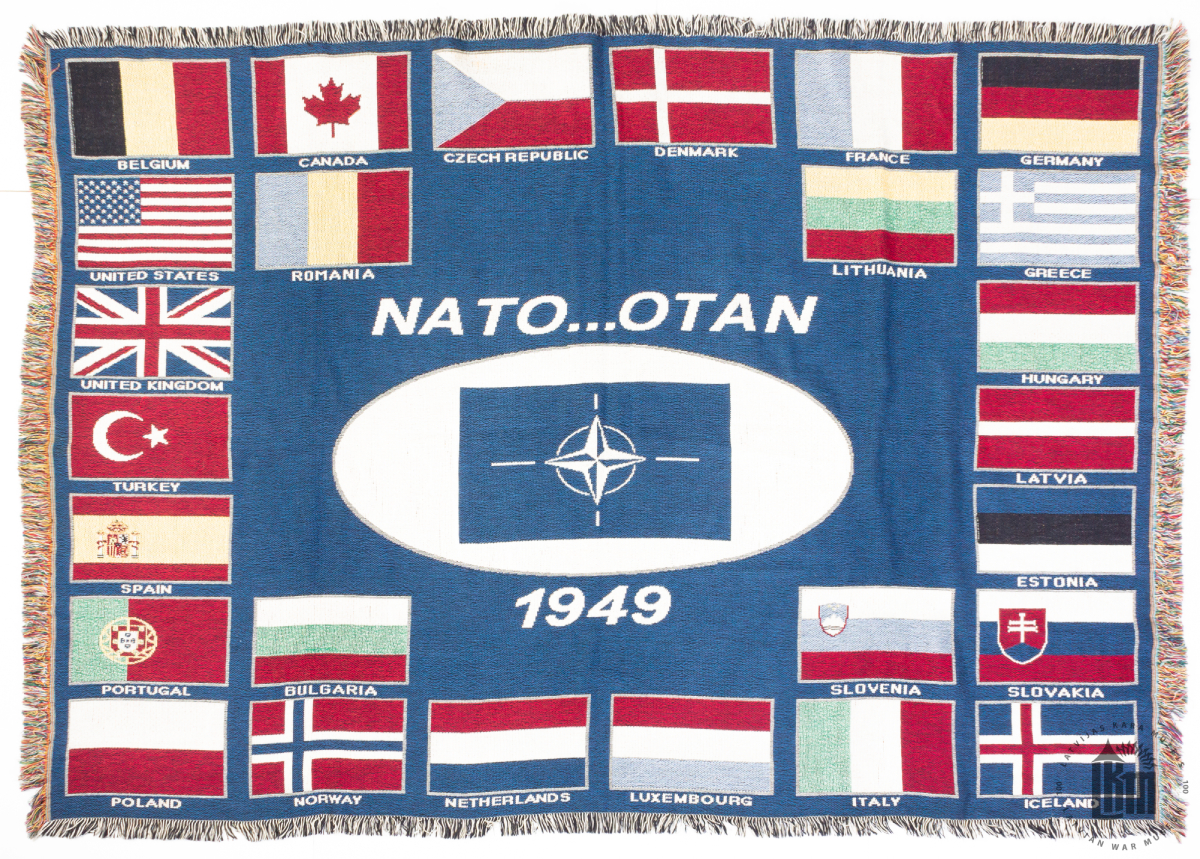 Sienas dekors ar NATO simboliku un 26 NATO dalībvalstu karogiem. Dāvināts viceadmirālim G. A. Zeibotam Briselē, atvadoties no kolēģiem NATO mītnē, sakarā ar atvaļināšanos no dienesta.